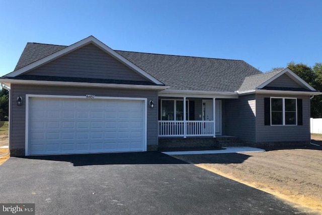 ranch-style home with covered porch, an attached garage, roof with shingles, and aphalt driveway