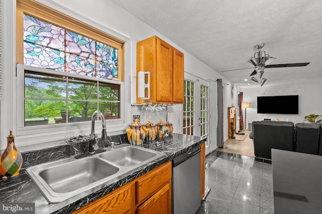 9525 Queens Guard Ct, Laurel, MD 20723 - kitchen featuring stainless steel dishwasher, a sink, dark countertops, plenty of natural light, and a textured ceiling