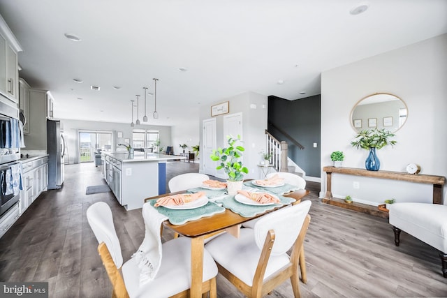 dining room with visible vents, baseboards, stairway, and wood finished floors
