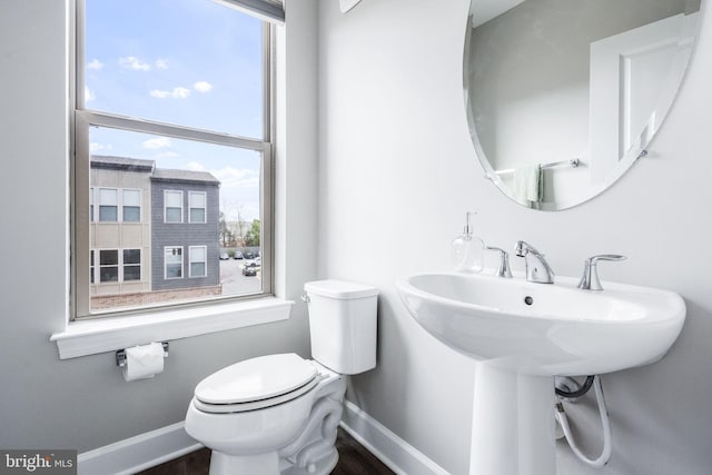 half bath featuring toilet, baseboards, and a wealth of natural light