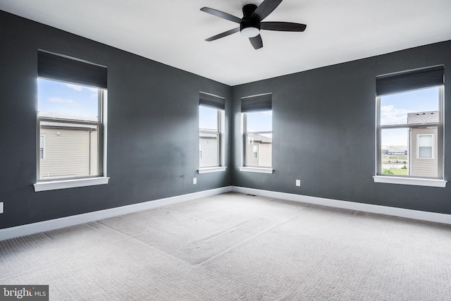 carpeted spare room with baseboards and a ceiling fan