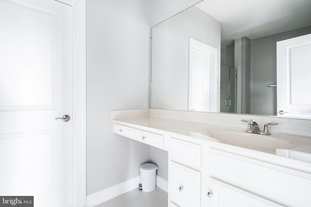 bathroom with baseboards, vanity, and a shower with door