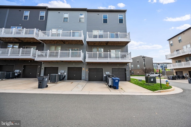rear view of house featuring central AC unit, an attached garage, and driveway