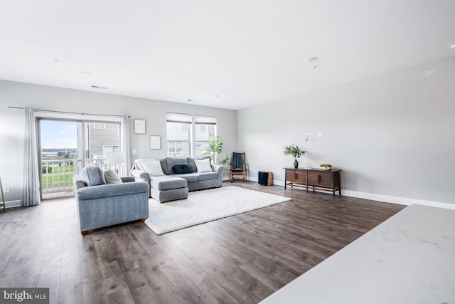 living room featuring dark wood-style floors, baseboards, and a healthy amount of sunlight