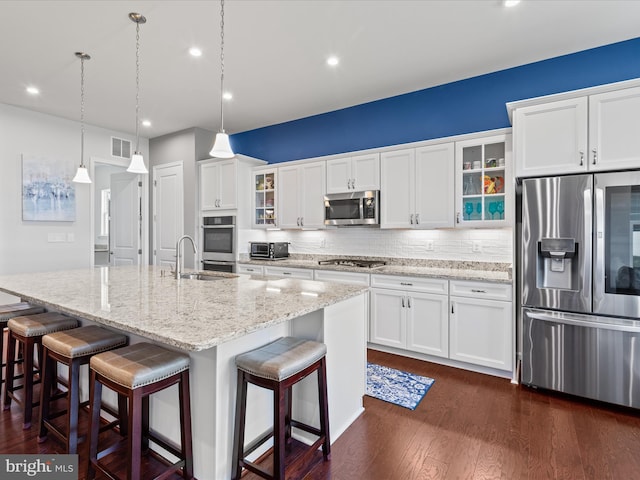 kitchen featuring dark wood-style flooring, visible vents, stainless steel appliances, a sink, and backsplash
