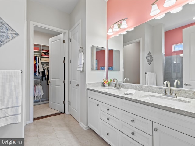 bathroom with double vanity, a sink, tile patterned floors, and a spacious closet