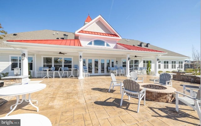 rear view of house featuring a fire pit, a standing seam roof, a ceiling fan, metal roof, and a patio