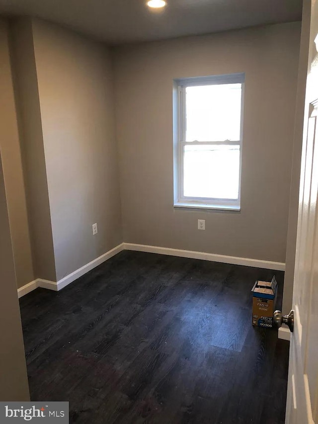 empty room featuring dark wood-type flooring and baseboards