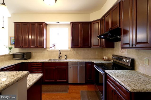 311 Treetops Dr, State College, PA 16801 - kitchen featuring dark wood-style floors, under cabinet range hood, stainless steel appliances, a sink, and hanging light fixtures