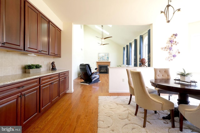 311 Treetops Dr, State College, PA 16801 - dining space with baseboards, ceiling fan, light wood-type flooring, vaulted ceiling, and a glass covered fireplace