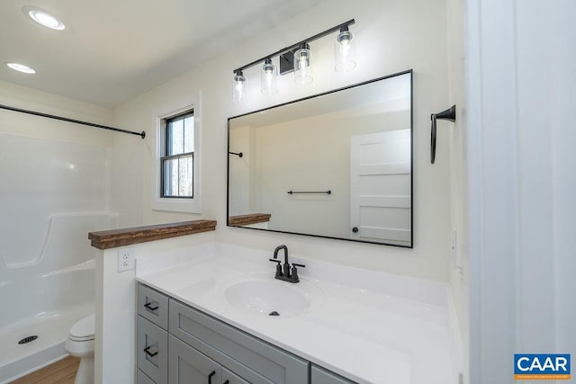 bathroom featuring toilet, a stall shower, recessed lighting, and vanity