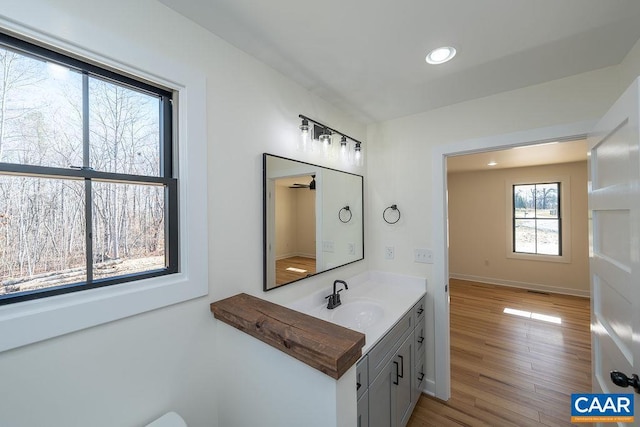 bathroom featuring baseboards, wood finished floors, recessed lighting, and vanity