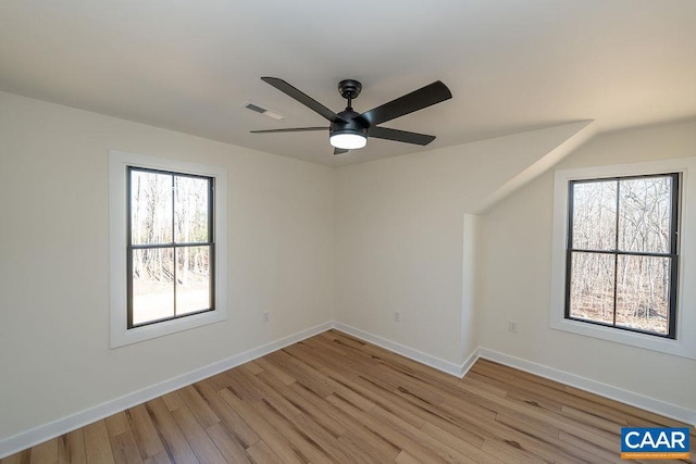 spare room with baseboards, ceiling fan, light wood-style flooring, and plenty of natural light
