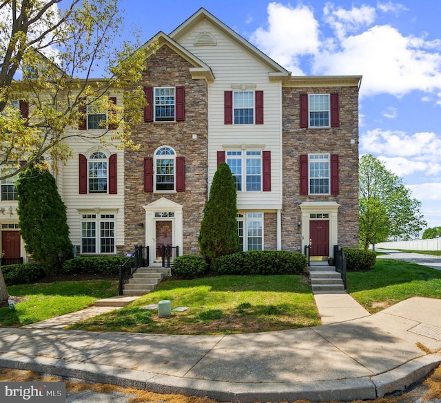 multi unit property with a front lawn and stone siding