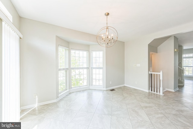 spare room with baseboards, arched walkways, a chandelier, and visible vents