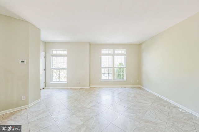 unfurnished room with light tile patterned flooring and baseboards