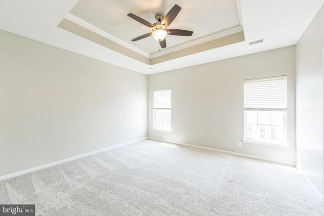 unfurnished room featuring a ceiling fan, visible vents, crown molding, carpet floors, and a tray ceiling