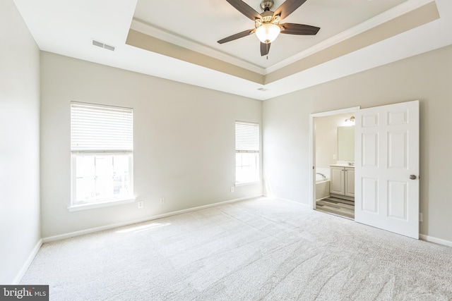 unfurnished bedroom with carpet floors, a tray ceiling, visible vents, and crown molding