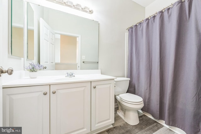 bathroom with vanity, curtained shower, toilet, and wood finished floors