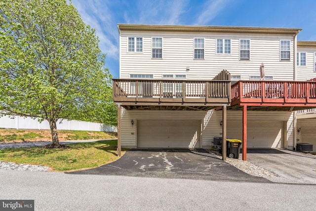 view of front of house with fence, an attached garage, a deck, central air condition unit, and driveway