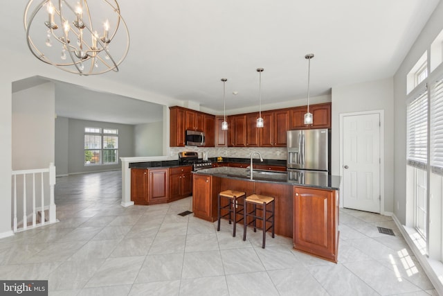 kitchen featuring an island with sink, stainless steel appliances, baseboards, backsplash, and visible vents
