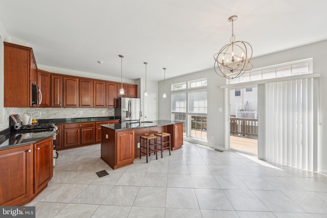 kitchen with dark countertops, appliances with stainless steel finishes, a sink, a chandelier, and a breakfast bar