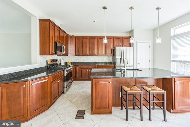 kitchen with a sink, appliances with stainless steel finishes, tasteful backsplash, and dark stone countertops