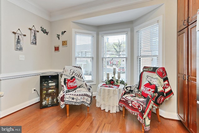 sitting room with baseboards, ornamental molding, and wood finished floors