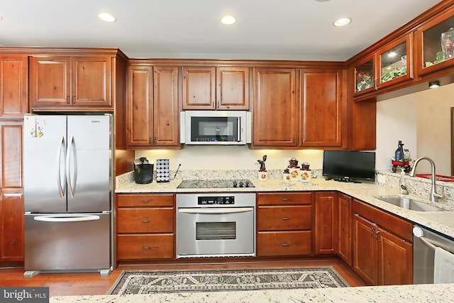 kitchen with recessed lighting, a sink, light stone countertops, and stainless steel appliances