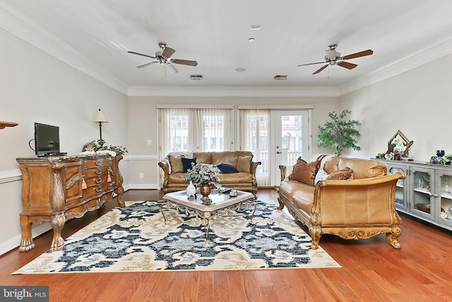 living area featuring wood finished floors, ornamental molding, a ceiling fan, and visible vents