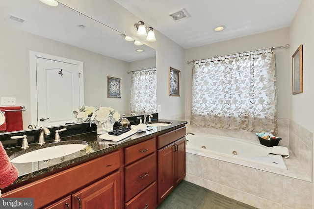 bathroom featuring a whirlpool tub, double vanity, visible vents, and a sink