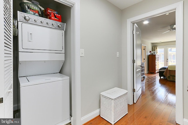 laundry room with french doors, light wood-style flooring, stacked washing maching and dryer, laundry area, and ceiling fan