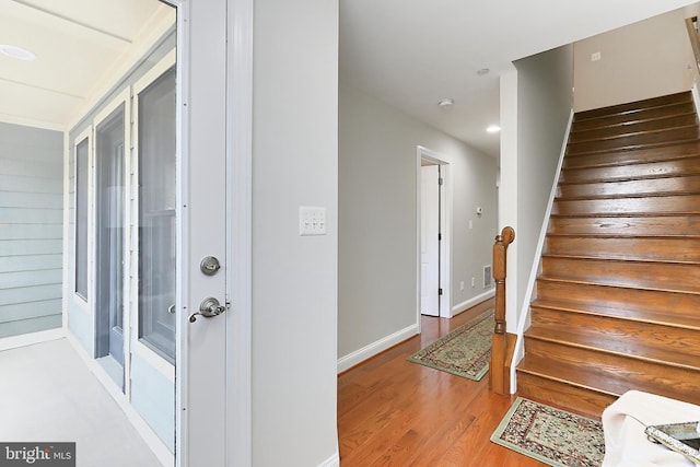 stairway with visible vents, baseboards, and wood finished floors
