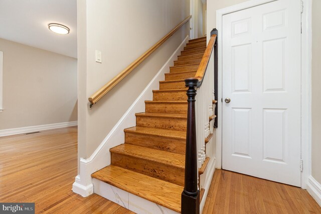 staircase featuring baseboards, visible vents, and wood finished floors