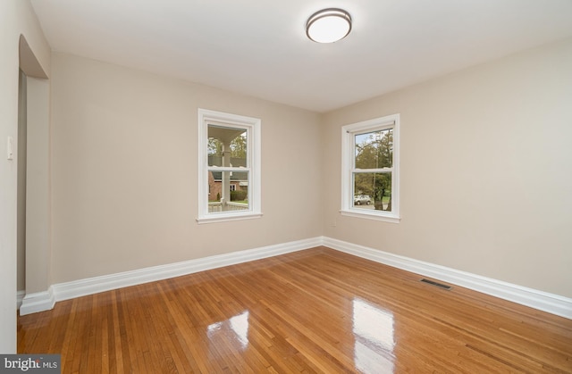 unfurnished room with baseboards, visible vents, and light wood-style floors