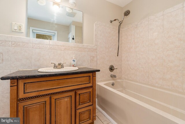 bathroom with tile patterned floors, bathing tub / shower combination, vanity, and tile walls
