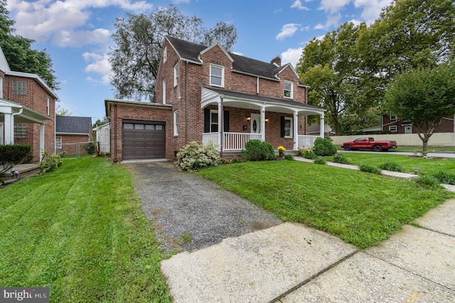 view of front of home featuring driveway, a front lawn, covered porch, brick siding, and a garage