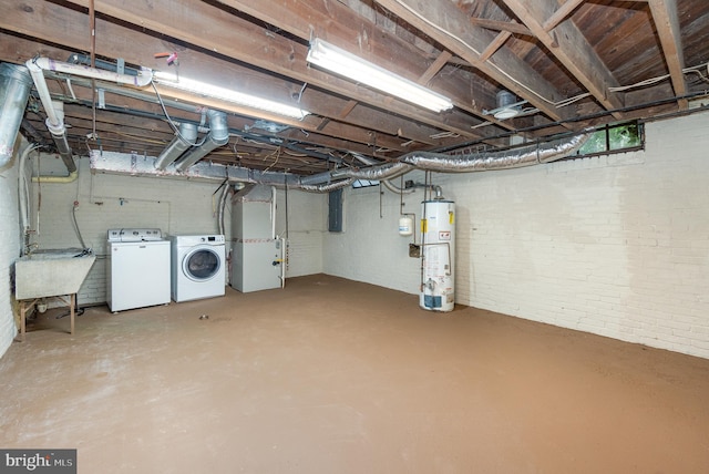 unfinished below grade area featuring heating unit, washer and clothes dryer, a sink, gas water heater, and brick wall