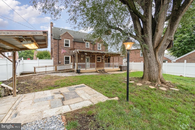 rear view of property with a fenced backyard, brick siding, a patio area, and a lawn