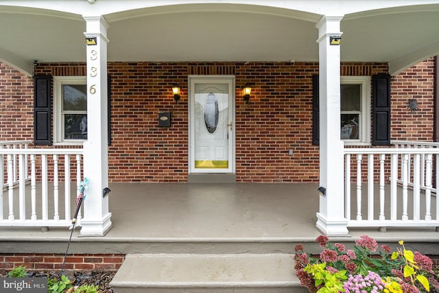entrance to property with covered porch and brick siding