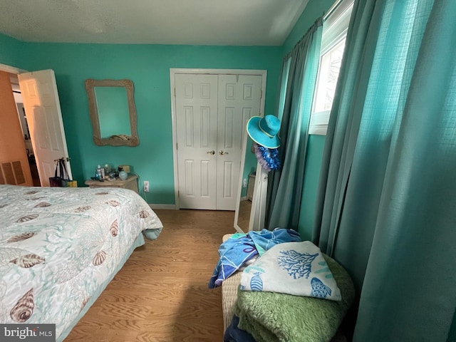 bedroom with wood finished floors, baseboards, and a closet