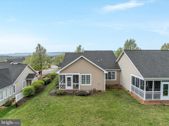 rear view of house with a sunroom, crawl space, central AC unit, a lawn, and roof with shingles