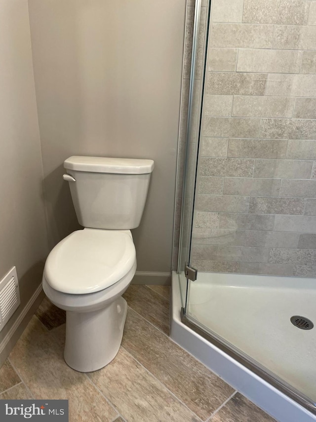 full bath with baseboards, visible vents, toilet, and a shower stall