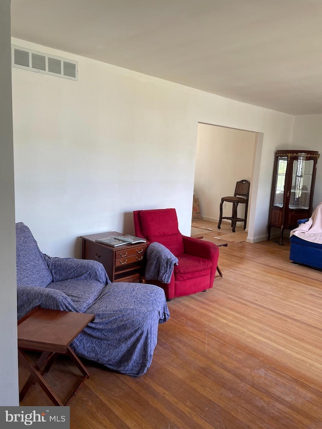 living area featuring visible vents and wood finished floors