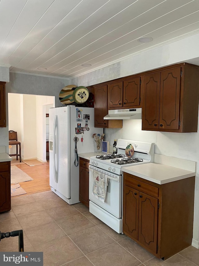 kitchen with light countertops, under cabinet range hood, white appliances, and ornamental molding