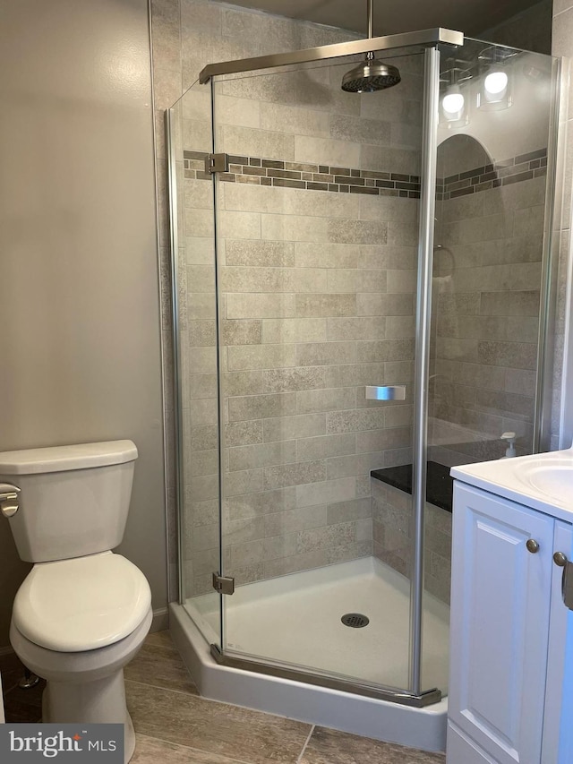 full bath featuring vanity, toilet, wood finished floors, and a stall shower