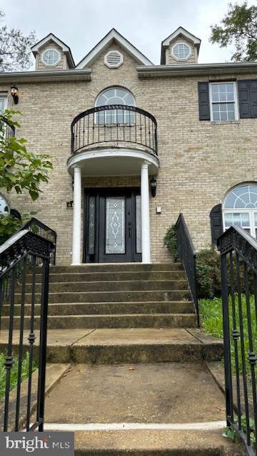 6411 L St, Capitol Heights, MD 20743 - view of exterior entry featuring brick siding, a balcony, a gate, and fence