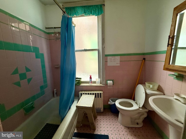 bathroom with radiator heating unit, a wainscoted wall, toilet, a sink, and tile walls