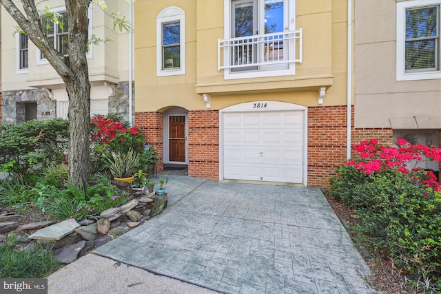 3814 Woodlawn Ct, Alexandria, VA 22304 - doorway to property with driveway, a garage, brick siding, a balcony, and stucco siding