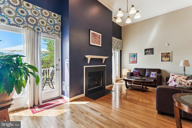 3814 Woodlawn Ct, Alexandria, VA 22304 - living room featuring crown molding, a high ceiling, a chandelier, a fireplace with flush hearth, and light wood-type flooring